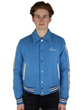 A young man with light brown hair models the Amiri Bones Jacket Mens by Zing Apparel, featuring a blue wool fabric, buttoned front, shirt-style collar, and "Amiri" embroidered on the chest, set against a white background.