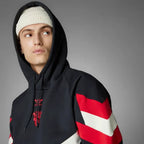 A person wearing a Zing Apparel Manchester United Originals Hoodie with red and white sleeve stripes and a white knit beanie looks off to the side against a plain gray background.