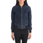A woman wears the Zing Apparel Ava Ma-1 Suede Bomber Jacket for women in blue, featuring a front zipper, flap pockets, and ribbed cuffs and hem, paired with black pants, standing against a white background.